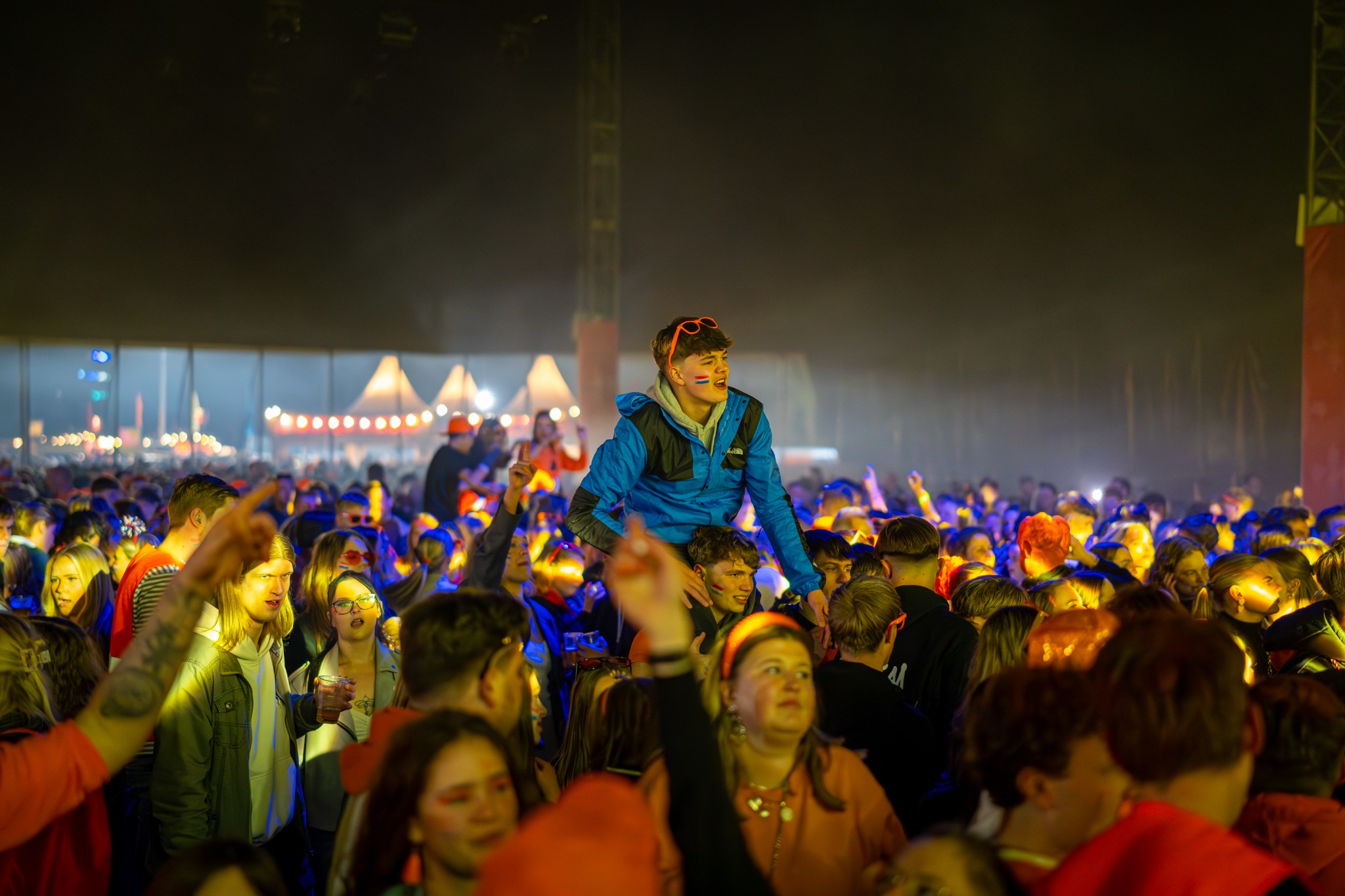 Publiek in feesttent met bezoeker op schouders